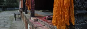 buddhistisches Gewand in orangener Farbe und religiöse Malereien in einem Tempel in Nepal