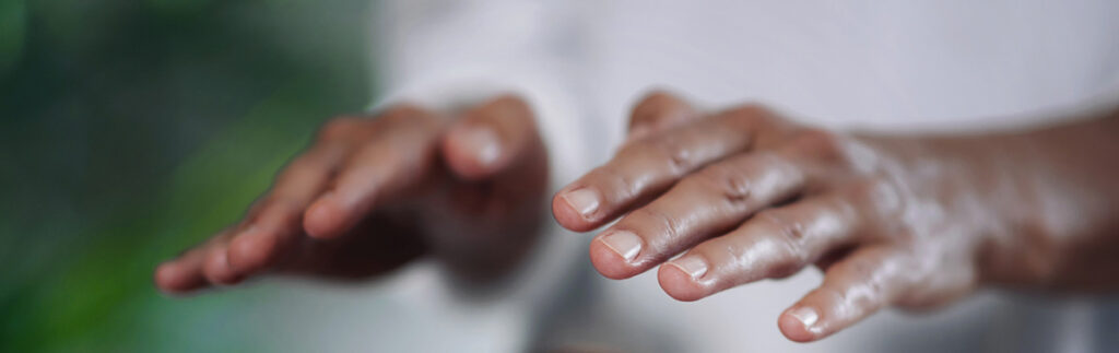 Hände zu sehen und weisses Shirt, Person praktiziert Reiki in einer Reiki-Sitzung