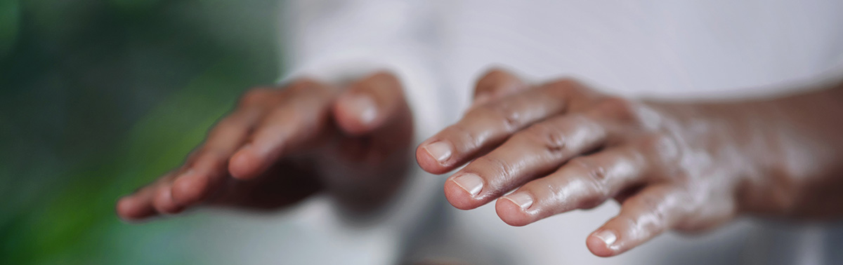 Hände zu sehen und weisses Shirt, Person praktiziert Reiki in einer Reiki-Sitzung