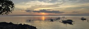 Sonnenuntergang in Panglao mit Schiffen im Vordergrund, ruhiges Meer, rote Sonne mit schöner Wolkenstimmung, Transformoon Symbolbild für Blog-Beitrag "der Körper folgt, die Seele führt: Wenn Zufall zum Plan wird"